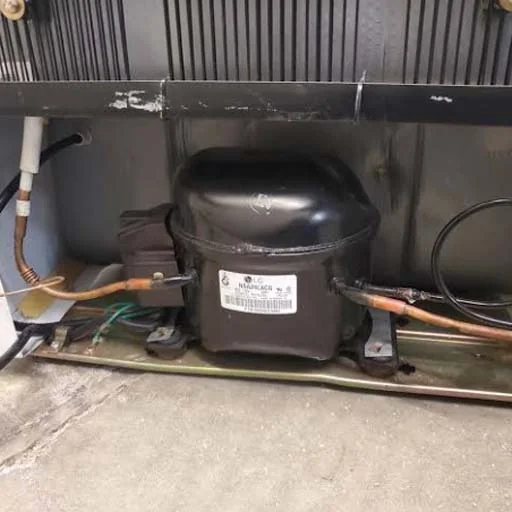 Fridge compressor and copper pipework at the base of a fridge