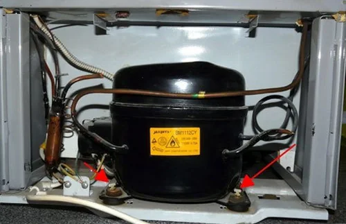 Fridge compressor at the back of the unit with its wiring and mounts