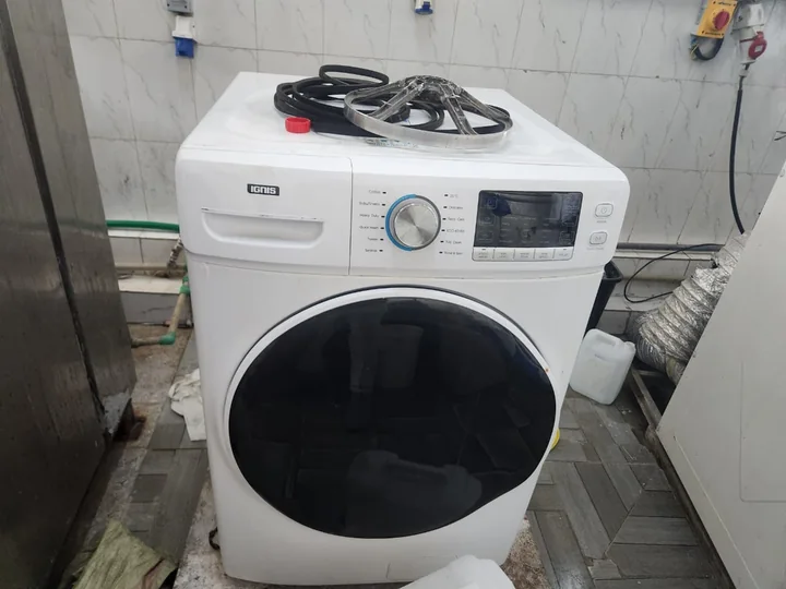 White front-load washing machine with tools laid out on top during a repair